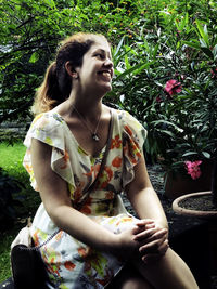 Young woman smiling while sitting by plants