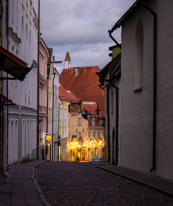 Street amidst buildings against sky at dusk