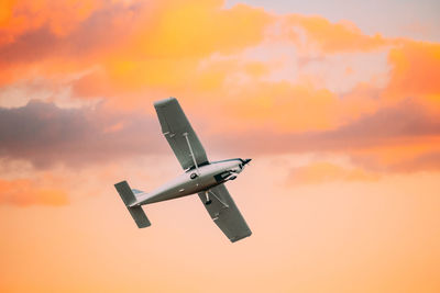 Low angle view of airplane flying against sky during sunset