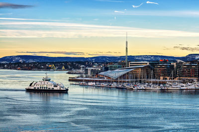 View of river by buildings against sky during sunset