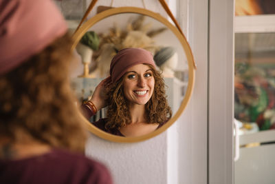 Confident designer smiles as she adjusts her headband in a mirror
