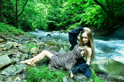 Woman sitting by tree in forest