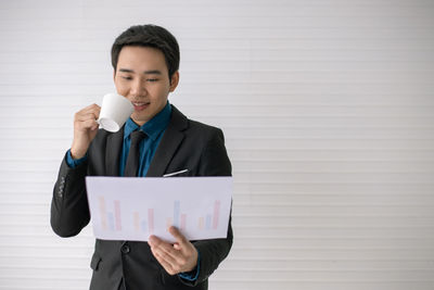 Man holding camera while standing against wall