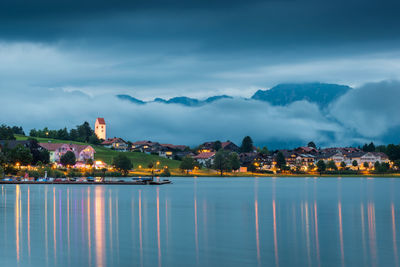 Scenic view of buildings by lake against mountains