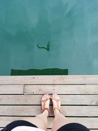 Low section of woman standing on pier by lake