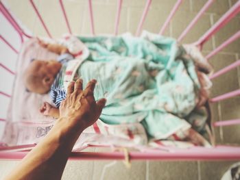 Close-up of person touching crib while baby sleeping