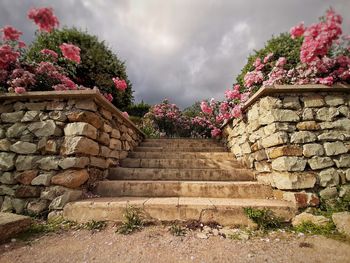 Stone wall by steps against sky