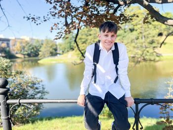 Happy teenage student wearing a white shirt with a backpack, standing outdoors