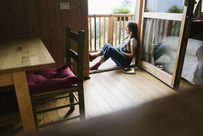 Happy young woman sitting in doorway