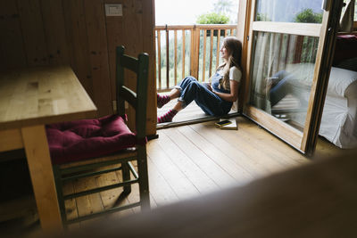 Happy young woman sitting in doorway