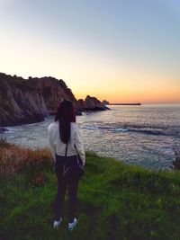 Rear view of woman standing on beach during sunset