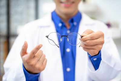 Midsection of doctor holding sunglasses