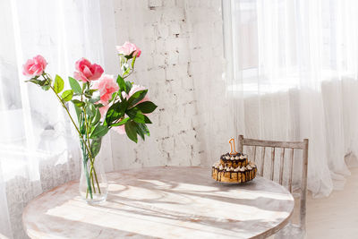 Flower vase and cake on table