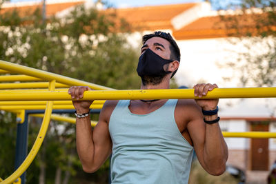 Athletic male exercising chin-ups in playground