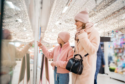 Mother and daughter look at the shop window of the shopping day