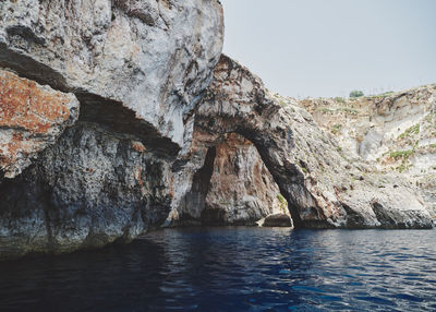 Rock formations in sea against clear sky