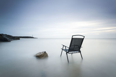 Lifeguard hut on rock in sea against sky