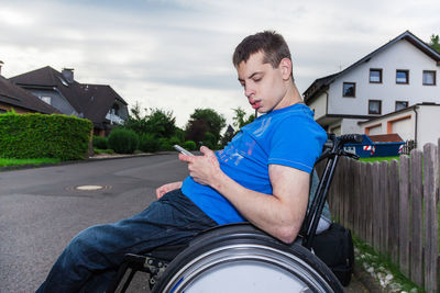 Disabled of man using mobile phone while sitting on wheelchair