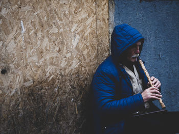 Man playing guitar against wall