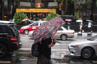 Man with umbrella on road in rainy season at bukit bintang kuala lumpur