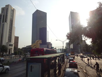 Cars on city street by buildings against sky