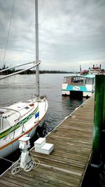 Boats in sea against cloudy sky