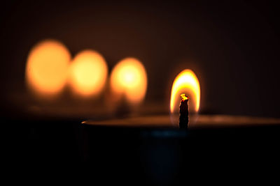 Close-up of lit candles in dark room