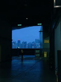 Illuminated city street by buildings against sky at night