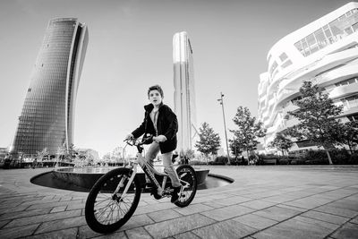 Full length of young woman on bicycle in city