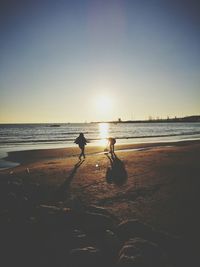 Silhouette person on beach against clear sky during sunset