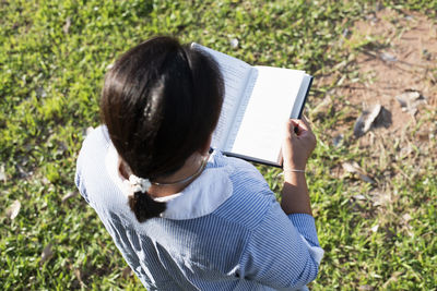 Rear view of woman using laptop while sitting on field