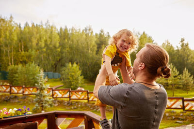 Faceless father playing with son in countryside