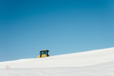 Low angle view of snow covered landscape against clear blue sky