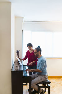 Man and woman using piano at home