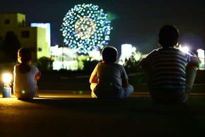 Rear view of people sitting in illuminated building