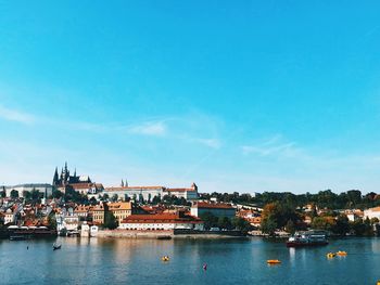 Town by river against blue sky