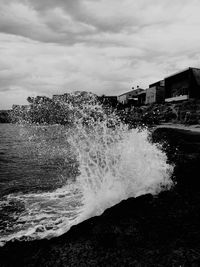 Waves breaking against sea against sky