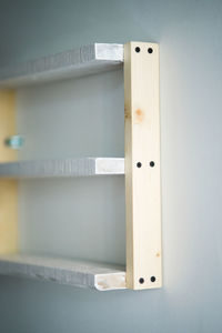 Empty white wooden pine shelves on white wall background.