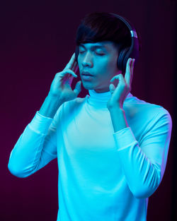 Man listening music while standing against black background