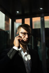 Serious businessman speaking on smartphone in hotel