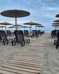 Chairs and tables on beach against sky