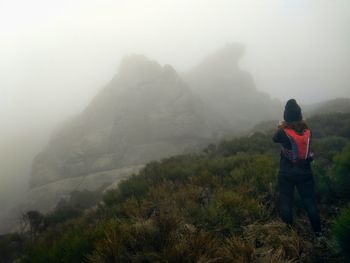 Rear view of a woman standing on mountain against fog