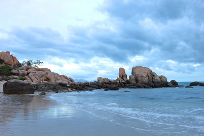 Rock formations on shore against sky
