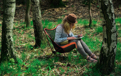 Young woman drawing on book in forest