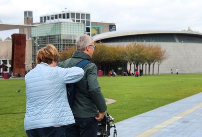 Rear view of man and woman standing on footpath