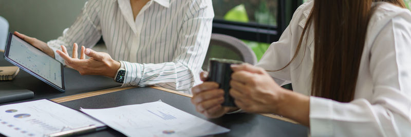 Coworker business concept, businesswoman drinking coffee and discussing new project with colleague.