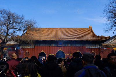 Group of people in front of building against blue sky