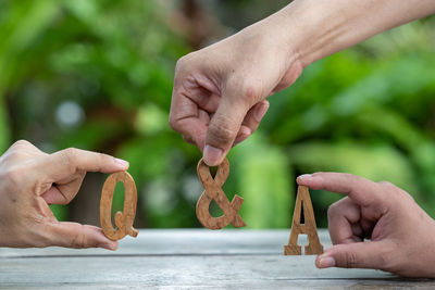 Cropped image of people holding hands against blurred background