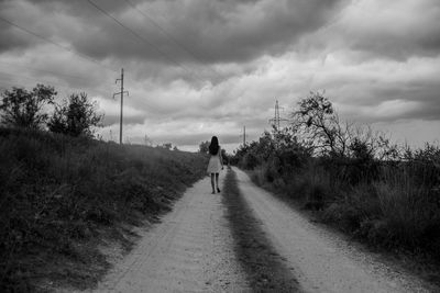 Rear view of man walking on road against sky