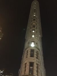 Low angle view of illuminated clock tower at night